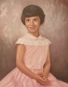 Young girl in a pink dress with a lace collar, smiling, posed portrait.