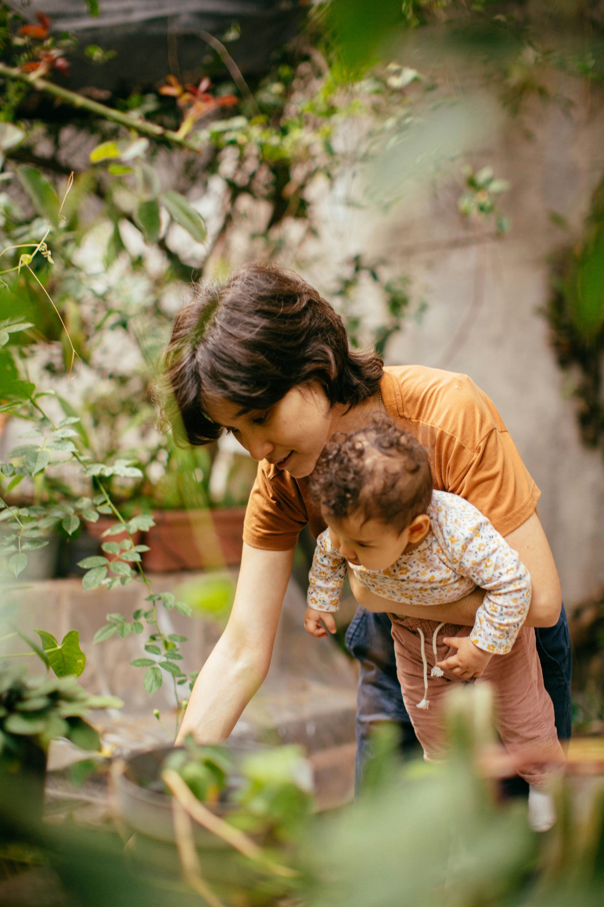 A woman is holding a baby in her arms in a garden.