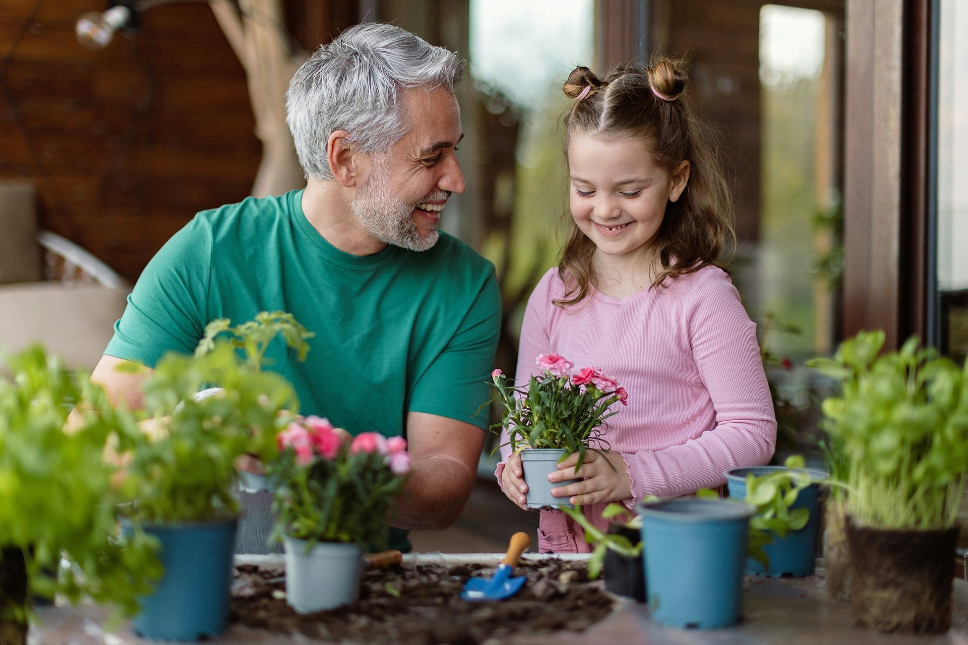 A man and a little girl are planting flowers in pots.
