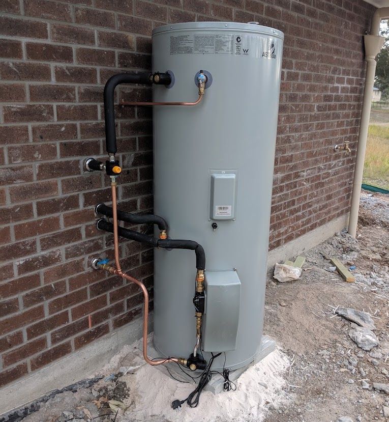 A Brick Wall With A Faucet And Pipes Attached To It — Country 2 Coast Plumbing And Gas In Wauchope, NSW 