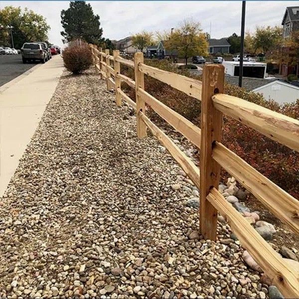 Wooden fence beside a gravel path along a sidewalk in a suburban neighborhood