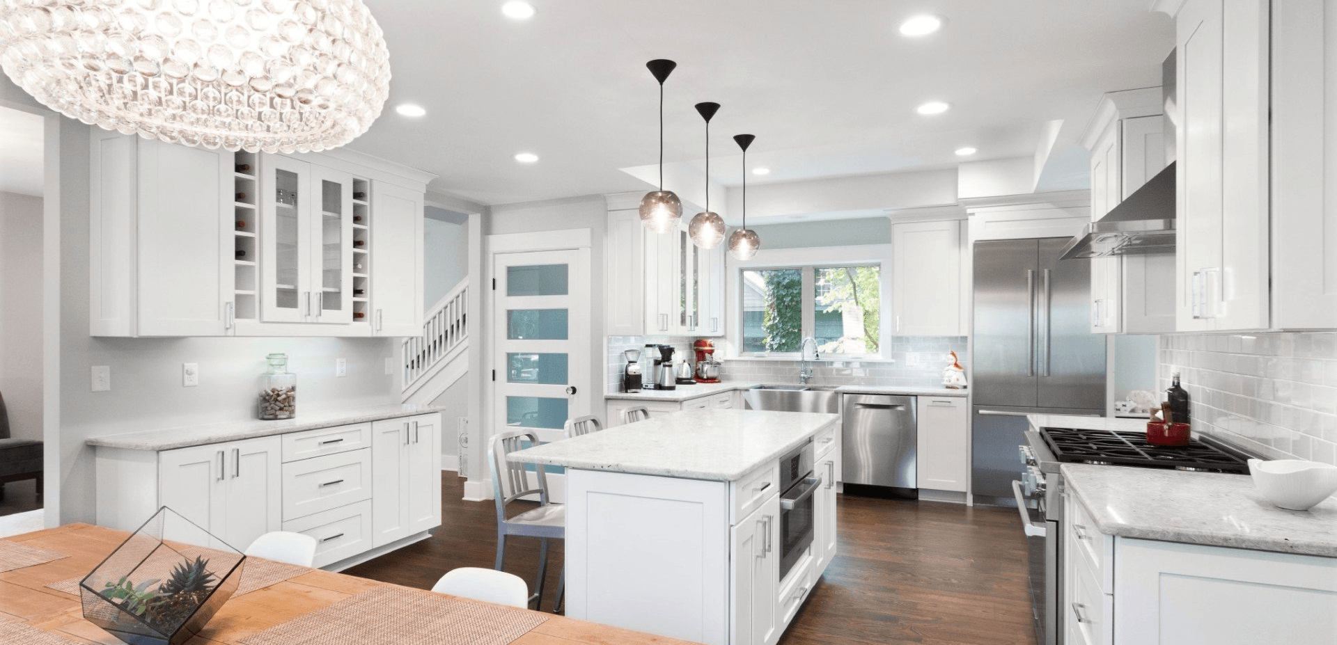 Bright white modern kitchen with island, pendant lights, and wood floors