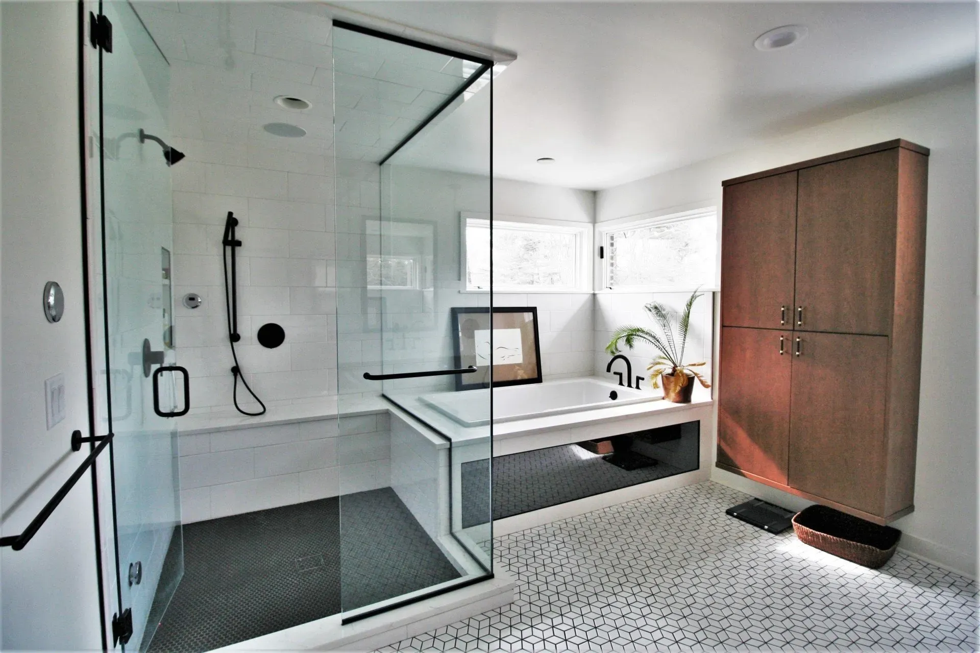 Modern bathroom with glass shower, white sink counter, patterned floor, and wooden cabinet