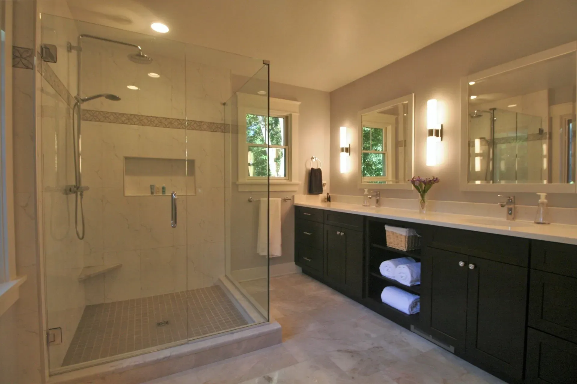 Modern bathroom with glass walk-in shower, double vanity, and large mirror