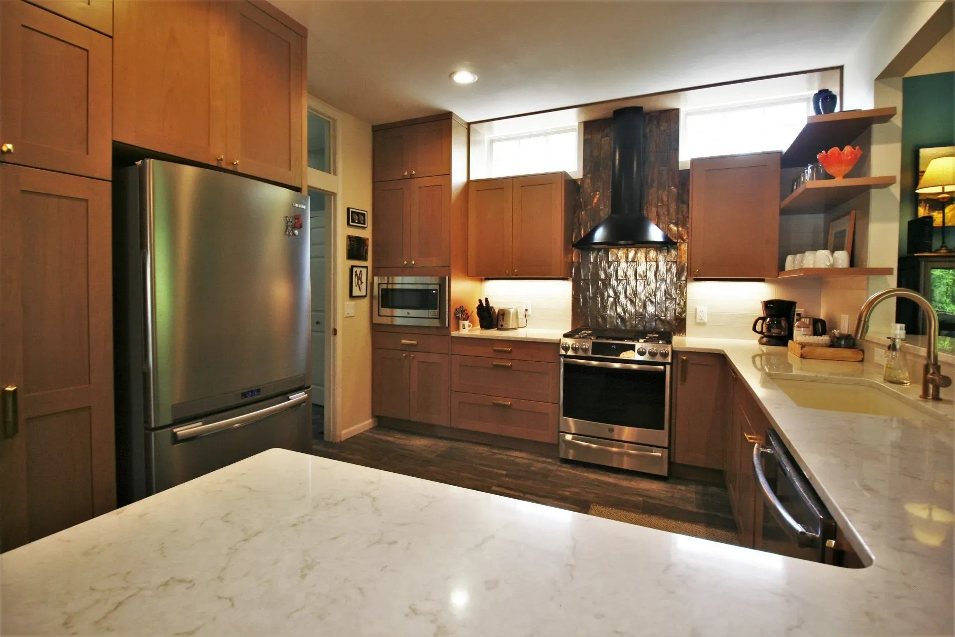 Modern kitchen with stainless steel appliances, dark wood cabinets, and a marble island countertop