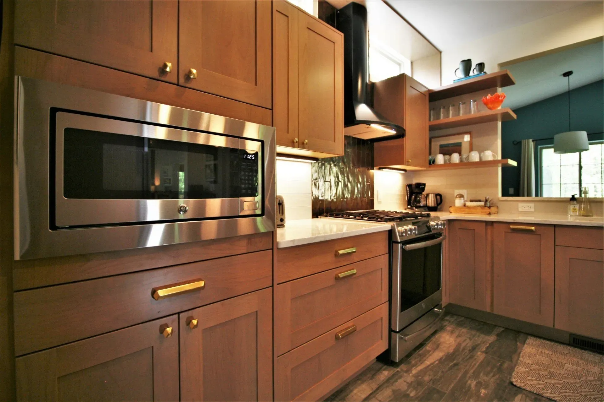 Modern kitchen with wood cabinets, stainless steel appliances, and a large island under warm lighting