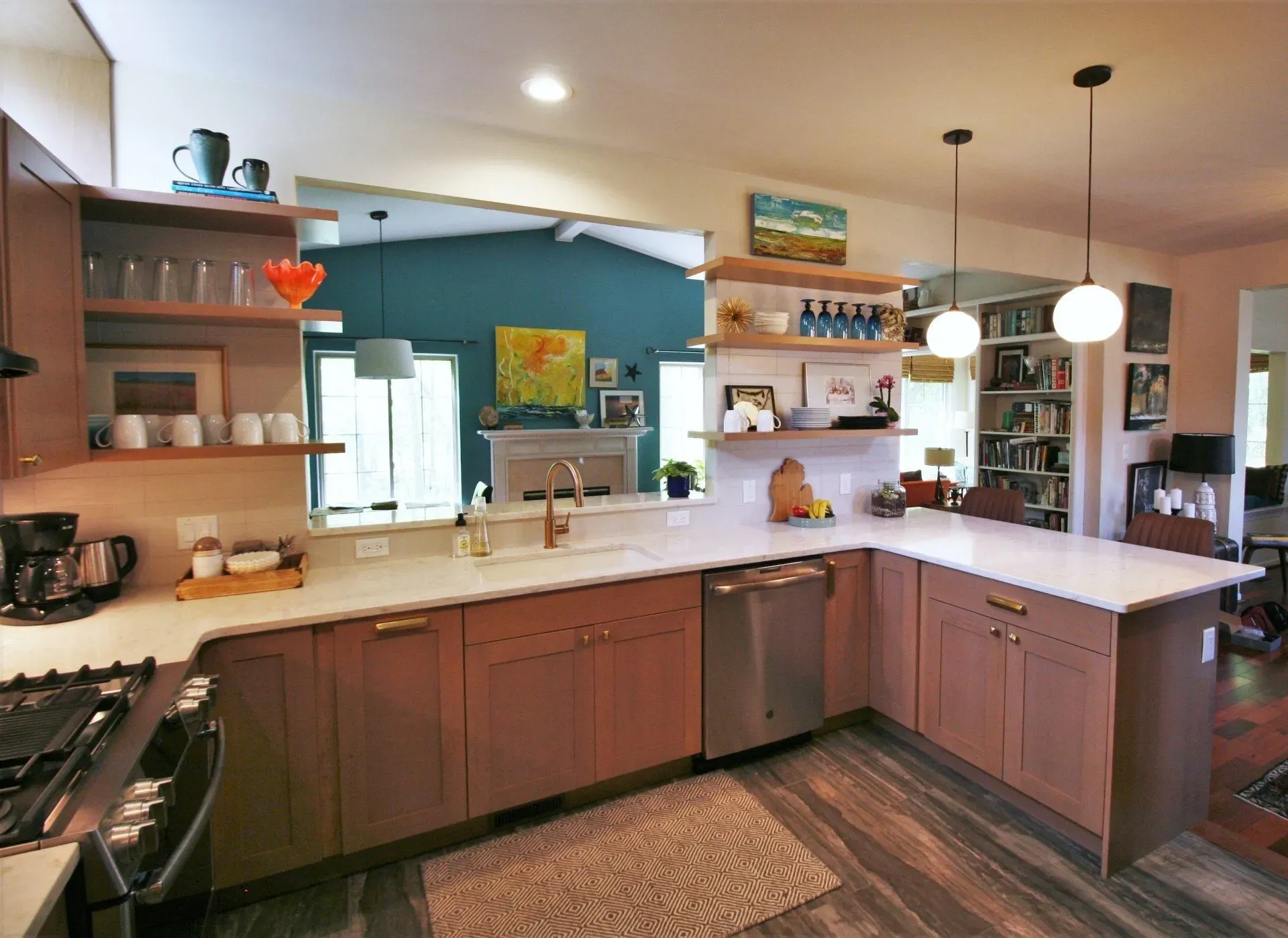 Modern kitchen with wood cabinets, white island, open shelves, pendant lights, and a blue accent wall.
