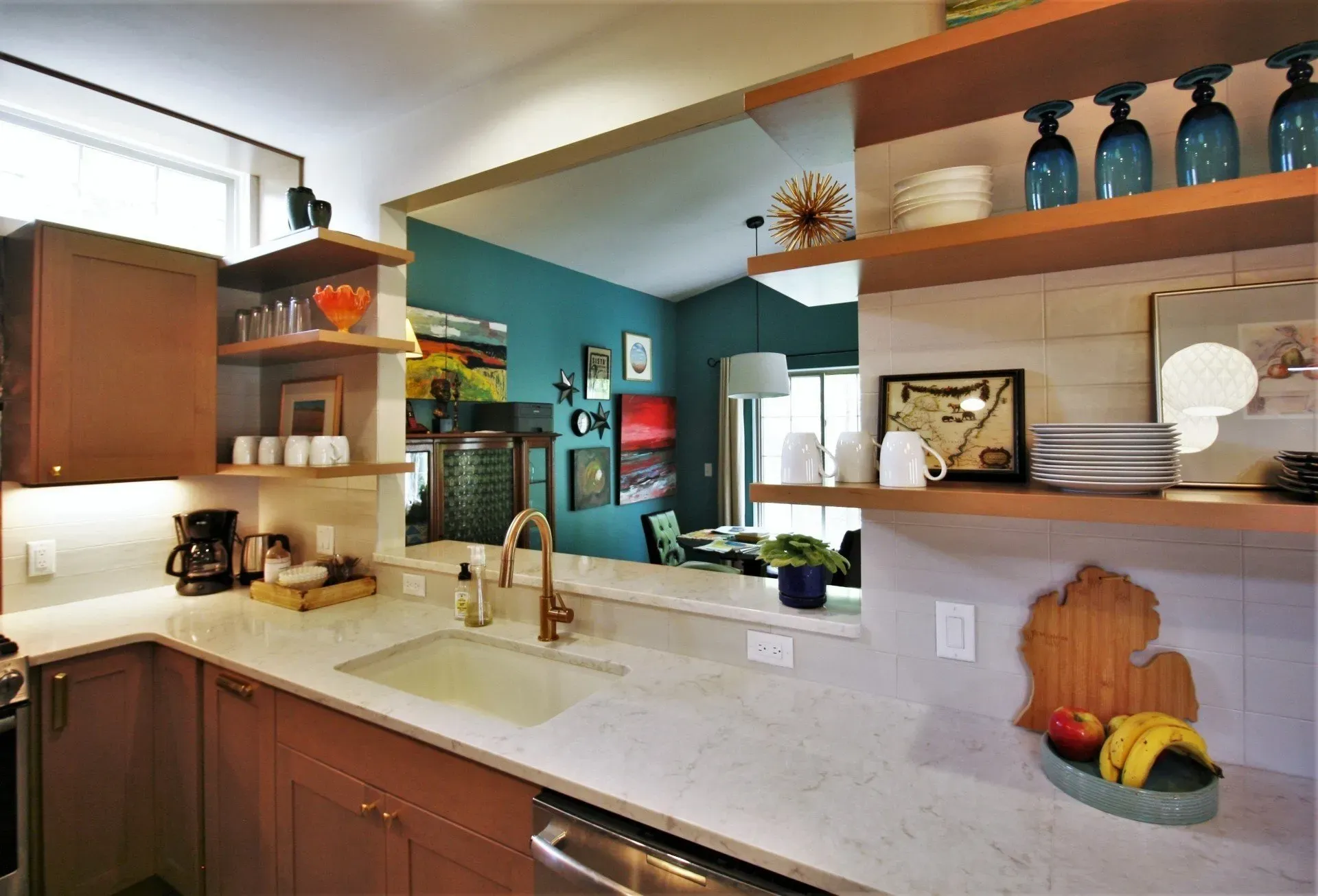 Modern kitchen with white countertops, wood cabinets, breakfast bar, and decorative shelves