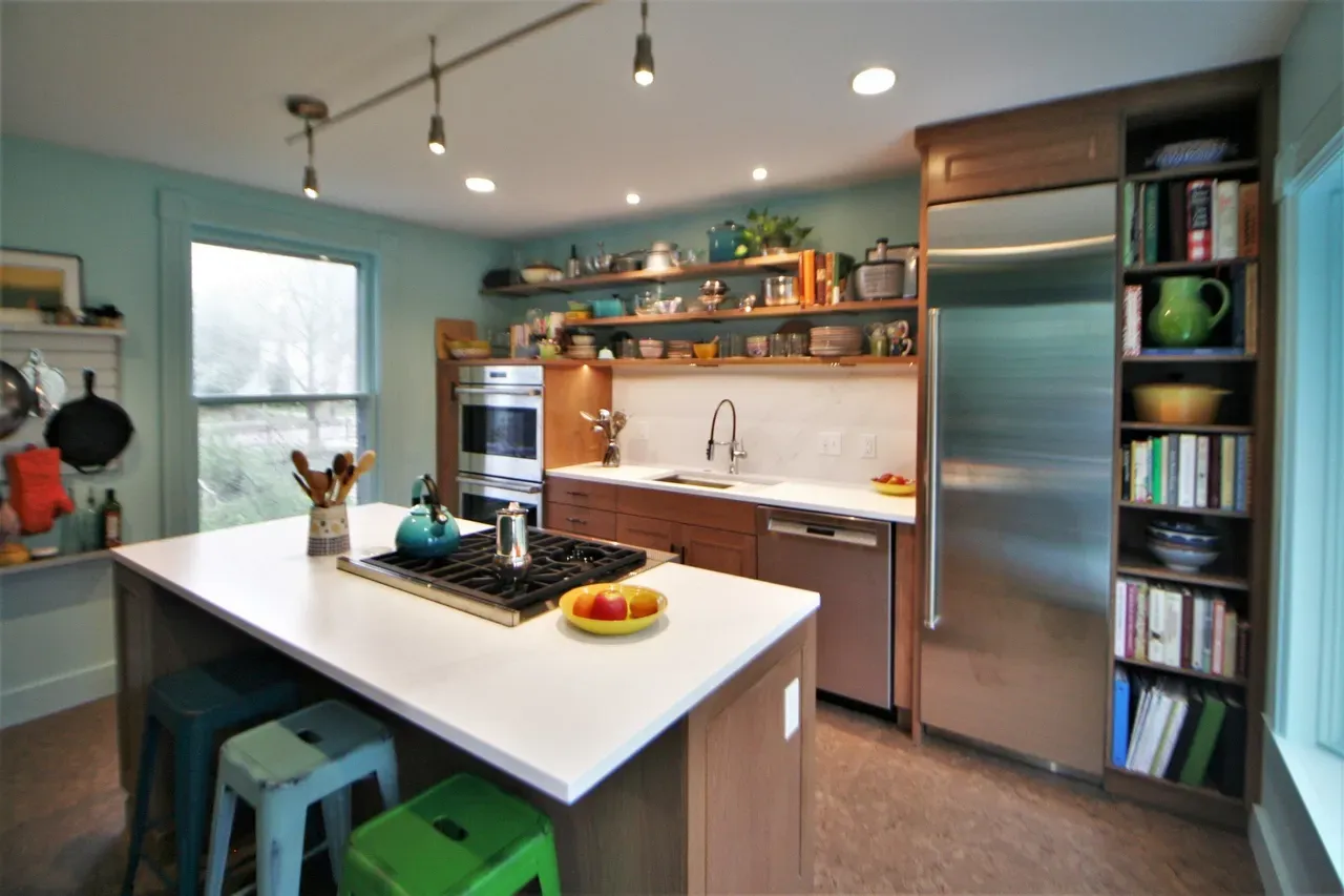 Modern kitchen with white island, stainless fridge, teal walls, and open shelves