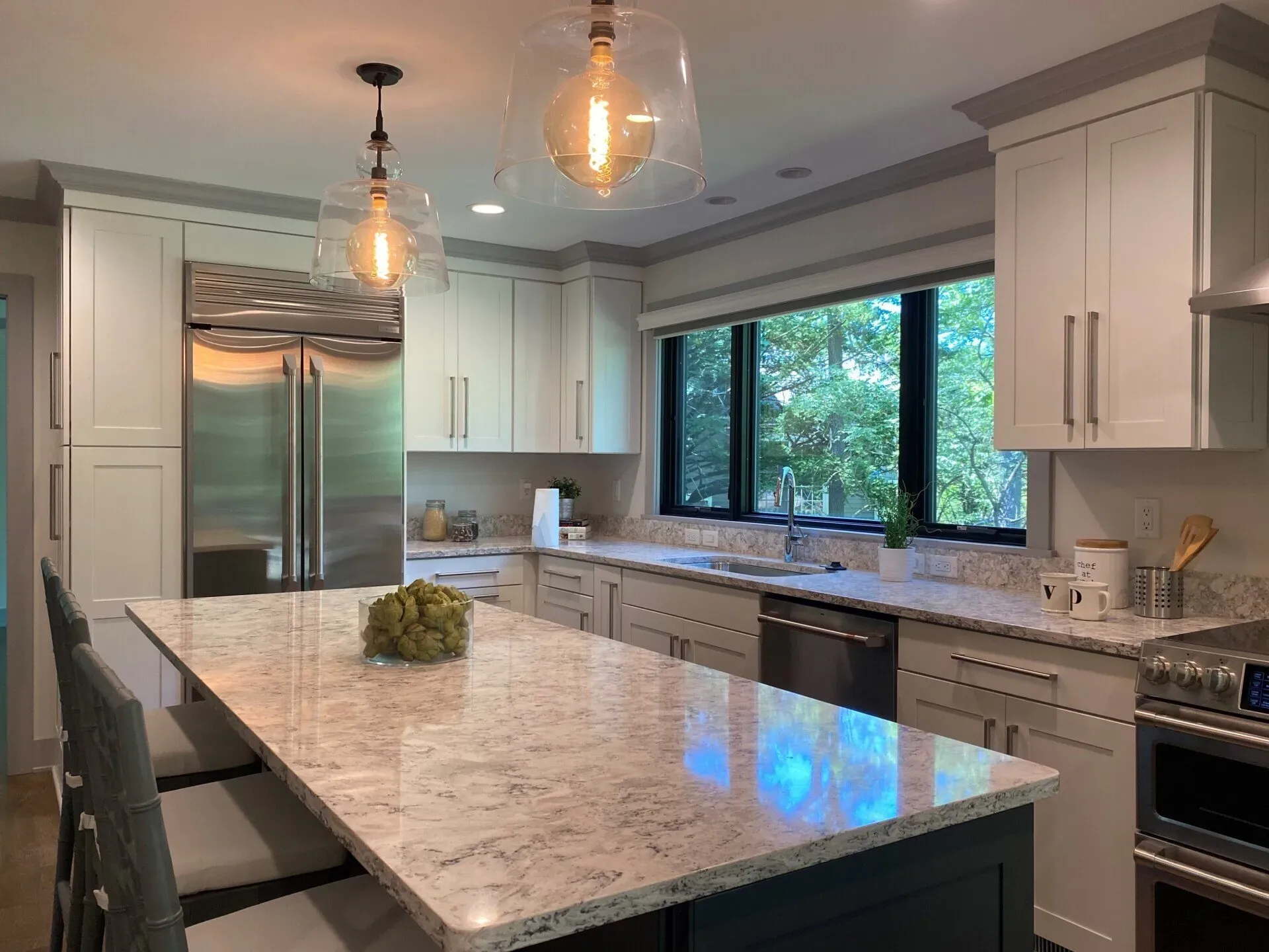 Modern kitchen with a large island, stainless steel appliances, white cabinets, and pendant lights