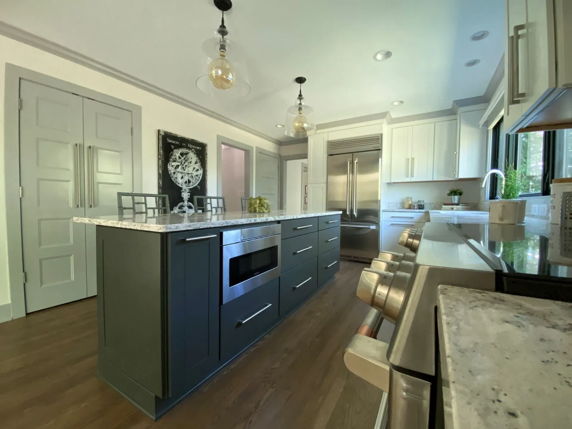 Modern kitchen with a central island, dark cabinets, stainless appliances, and wood floors