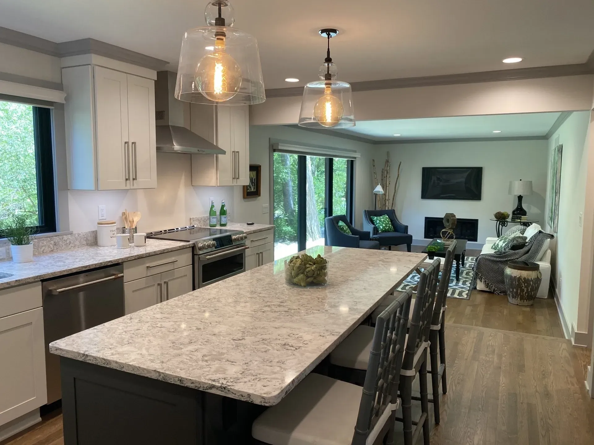 Open kitchen and living area with large island, pendant lights, and wood flooring