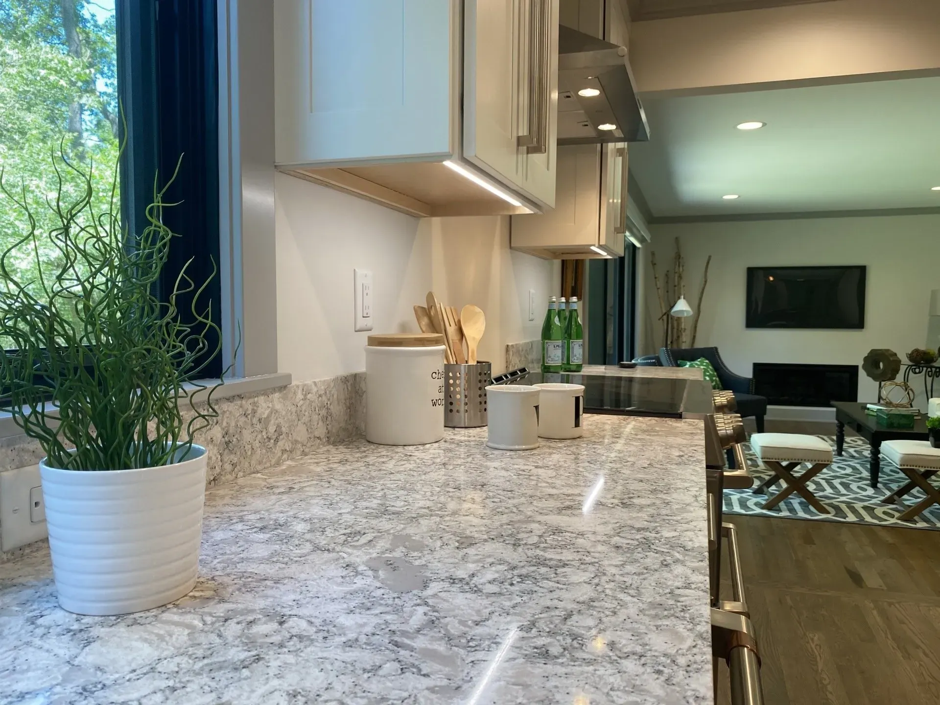 Bright kitchen countertop with white plant pot and modern living room in the background