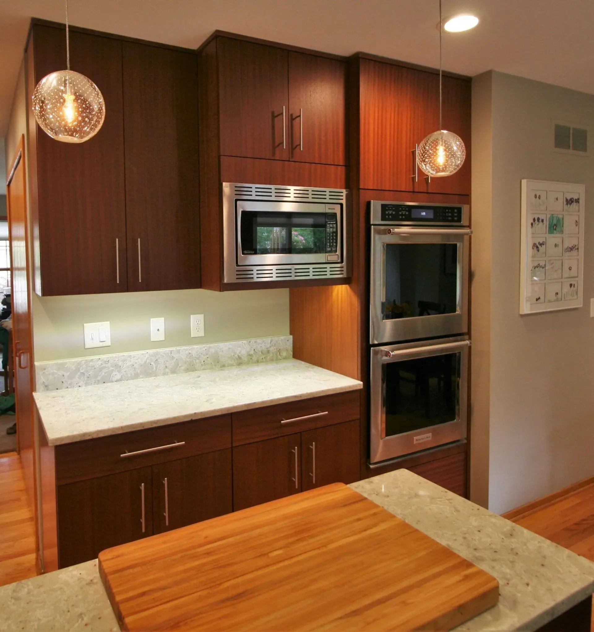 Modern kitchen with wooden cabinets, stainless steel built-ins, granite counters, and pendant lights
