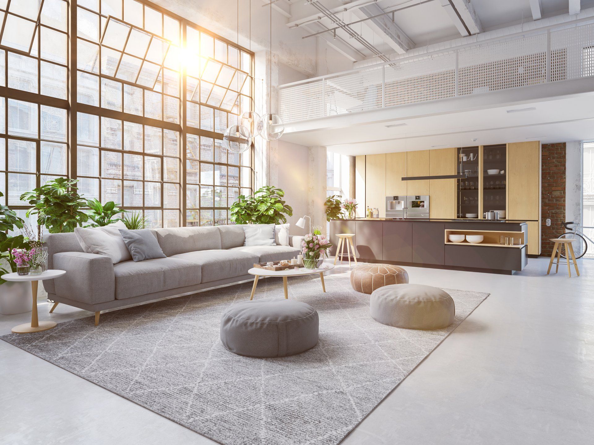 Bright airy loft living room with gray sofa, poufs, rug, plants, and large sunlit windows
