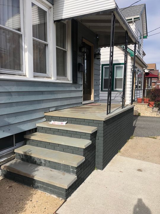 Blue house exterior with concrete steps leading to a small front porch and doorway Blue house exterior with concrete steps leading to a small front porch and doorway