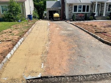 Driveway under construction beside a house, with fresh concrete and a yellow cement mixer in the garage. Driveway under construction beside a house, with fresh concrete and a yellow cement mixer in the garage.