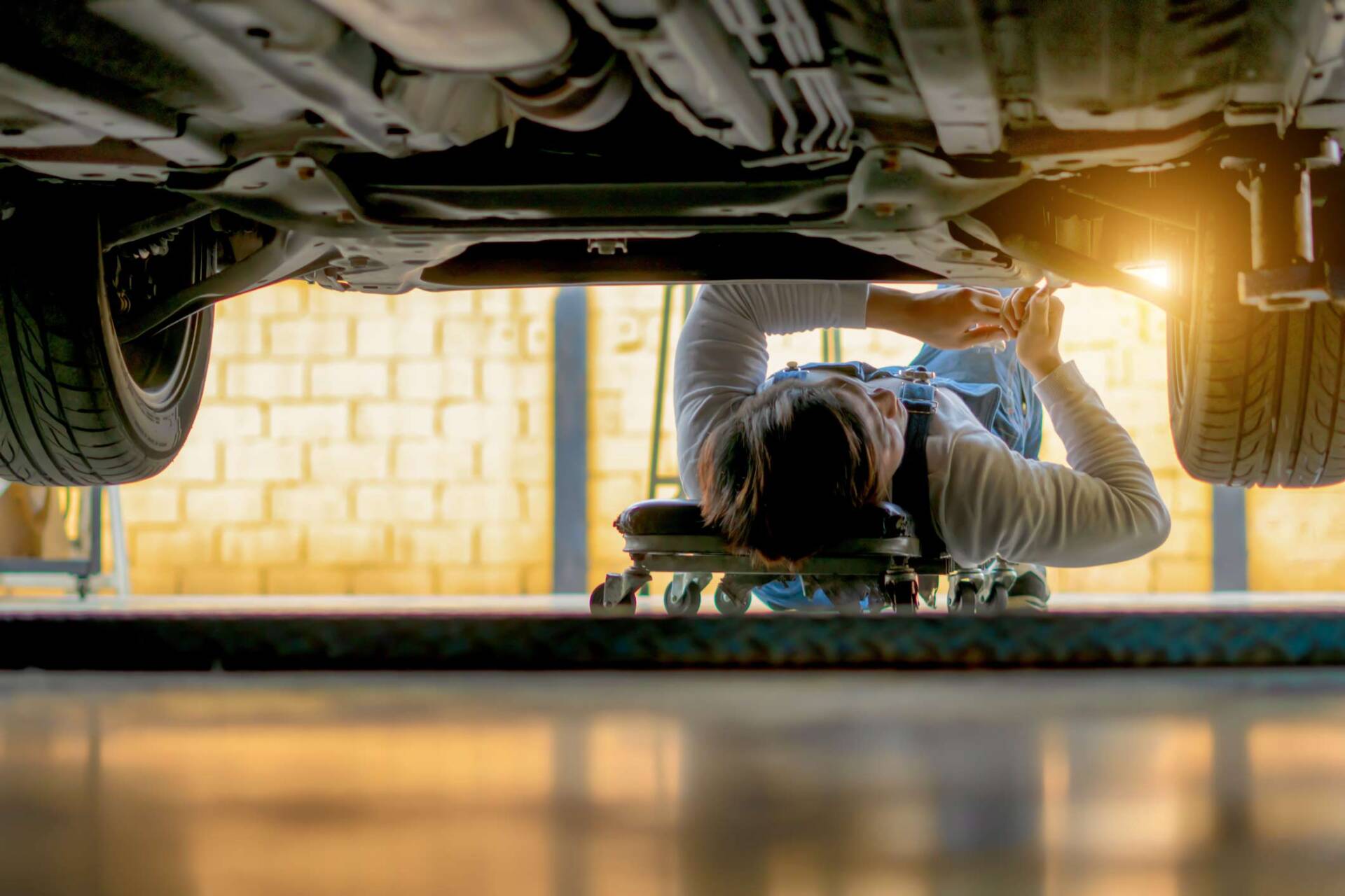 Person checking bottom of car — St. Clairsville, OH — Jeff's Auto Body & Collision Center