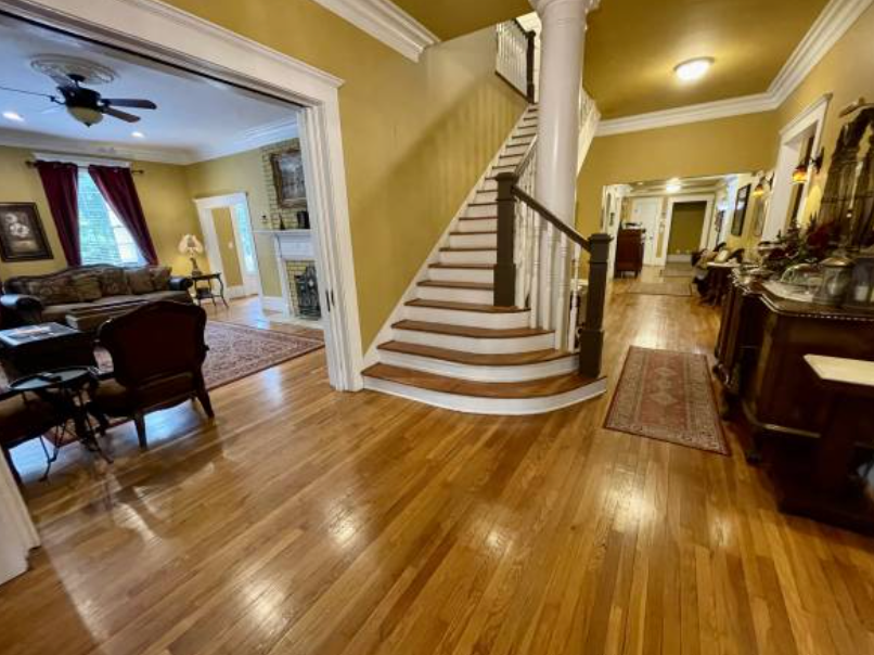 A living room with hardwood floors and stairs leading up to the second floor.