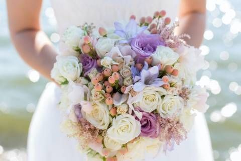 A bride in a white dress is holding a bouquet of flowers.