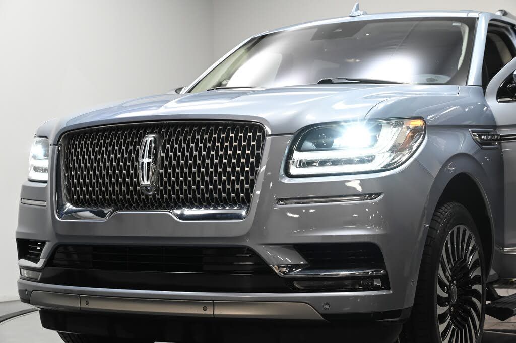Silver Lincoln SUV front view with illuminated headlights on a white studio background