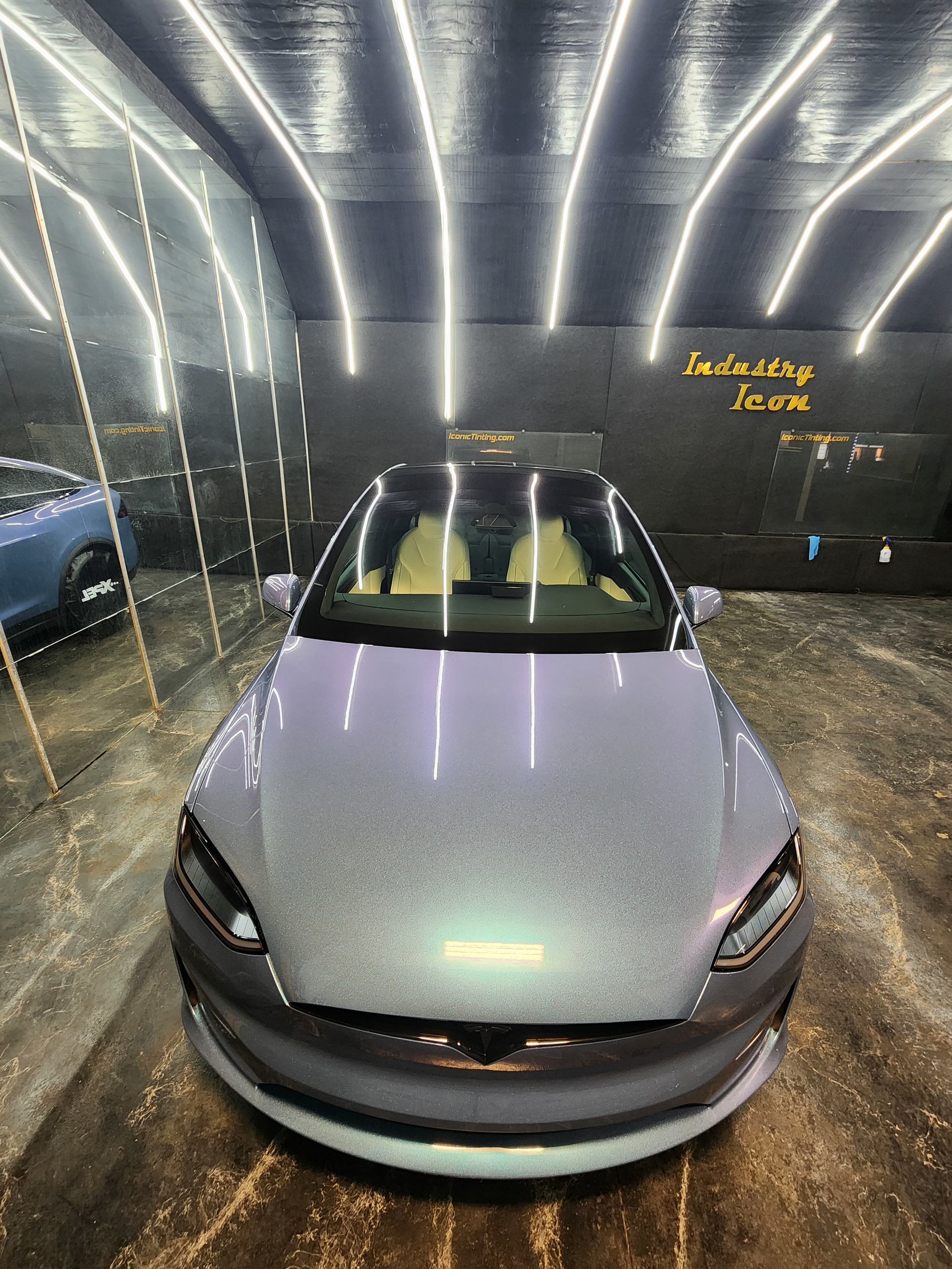 Person smoothing pink vinyl wrap over a car body in an auto repair shop
