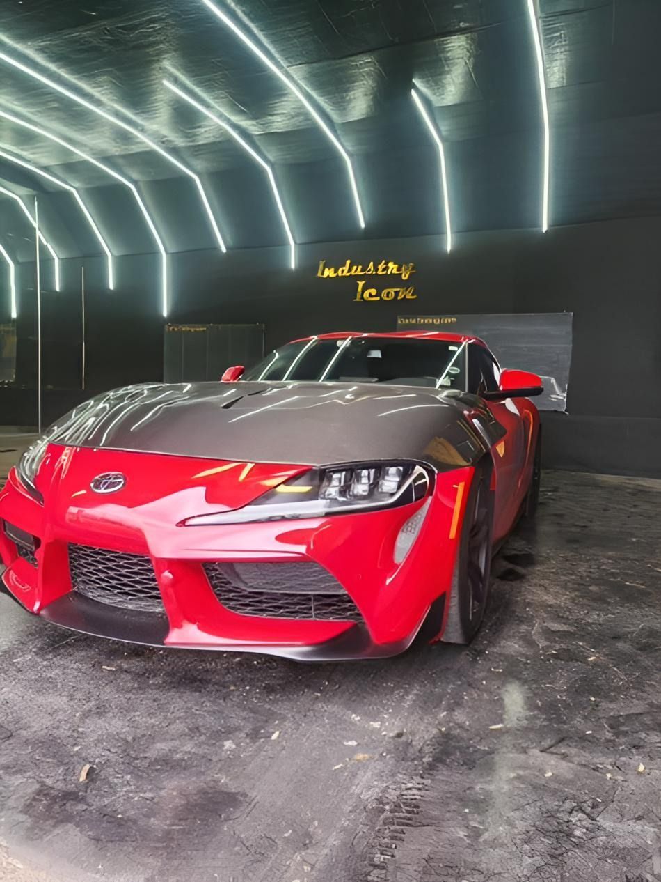 Red sports car with black hood parked in a dimly lit tunnel or garage.