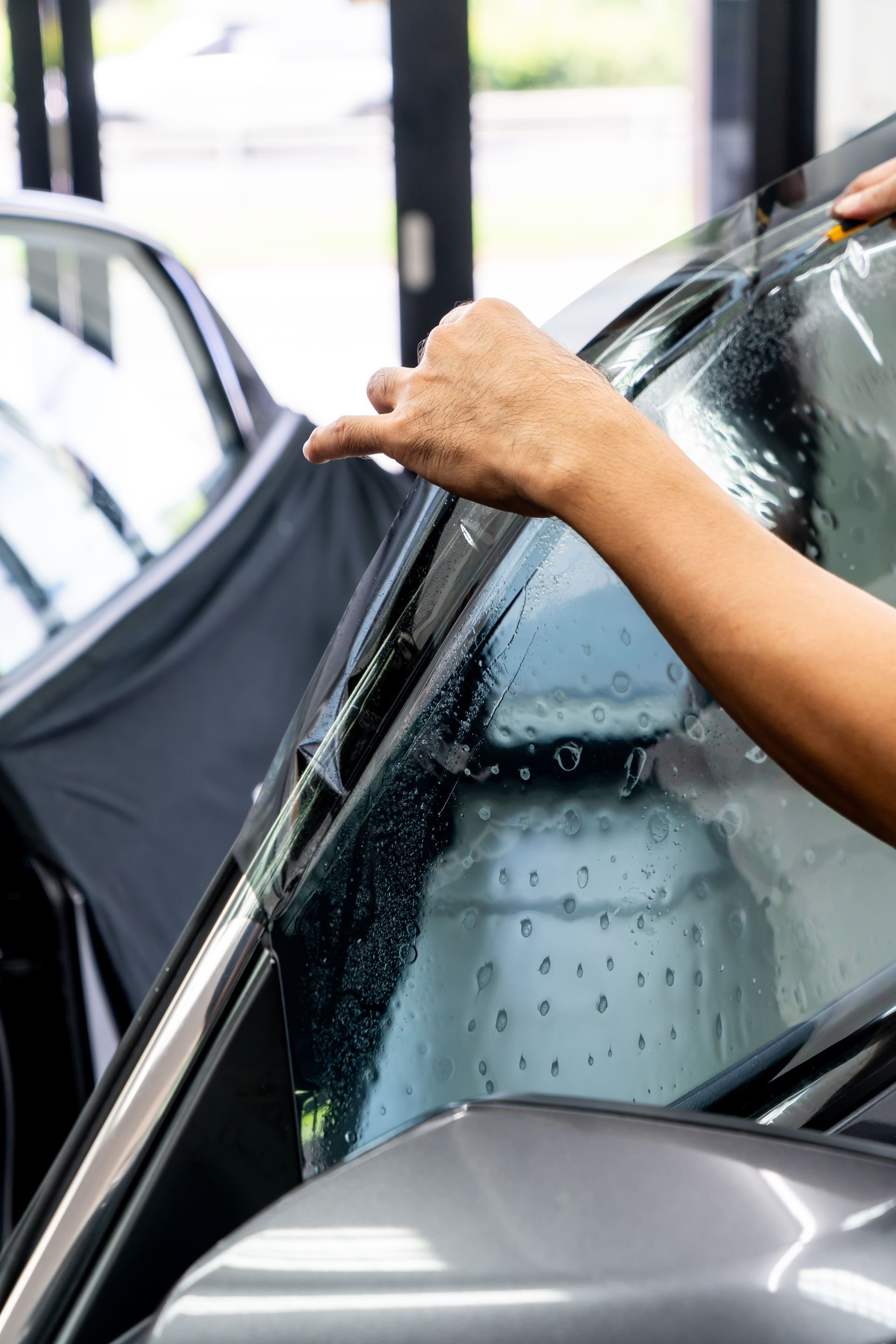 Hands applying a tint film to a car window with a squeegee