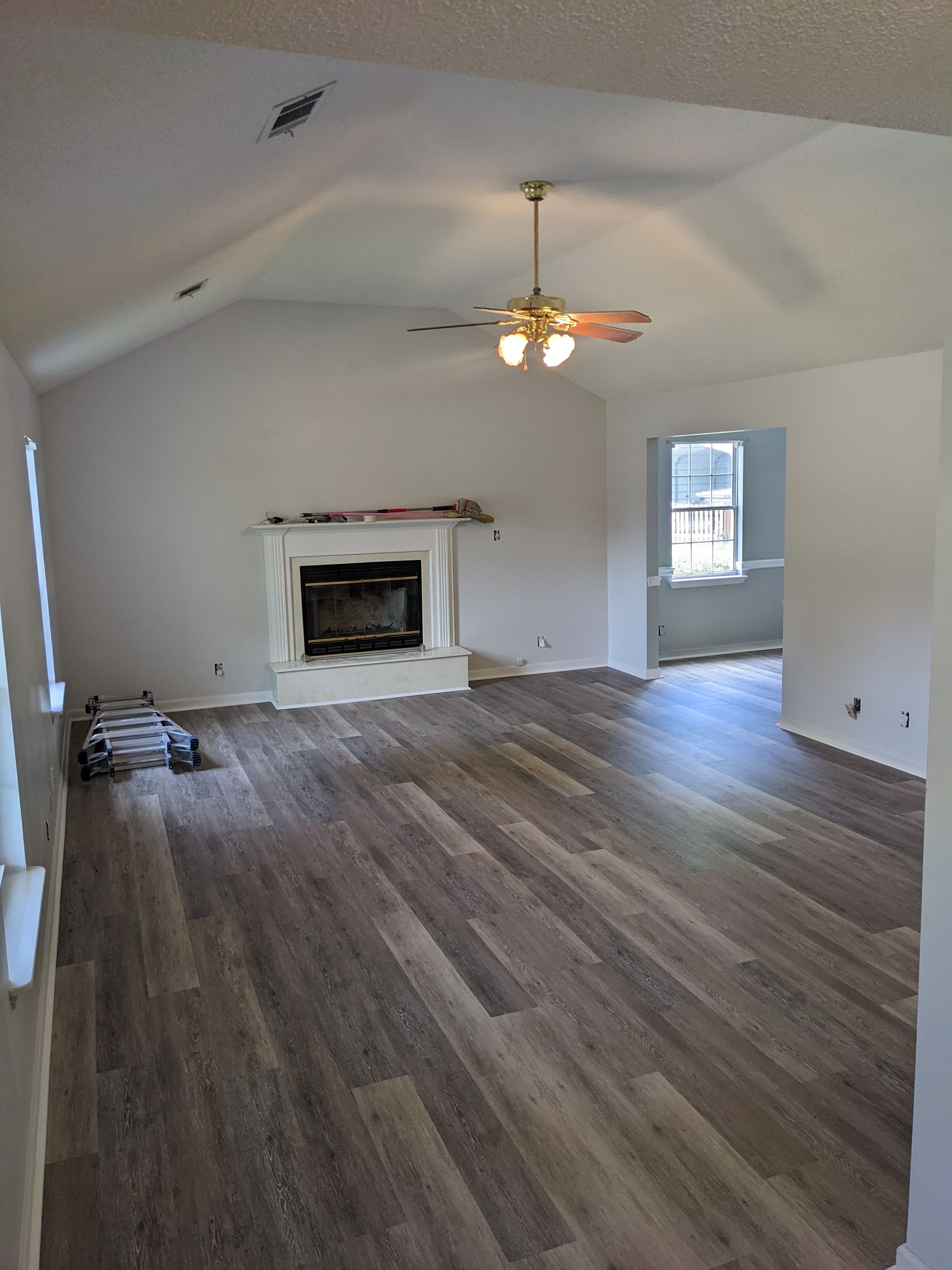 An empty living room with a fireplace and a ceiling fan.