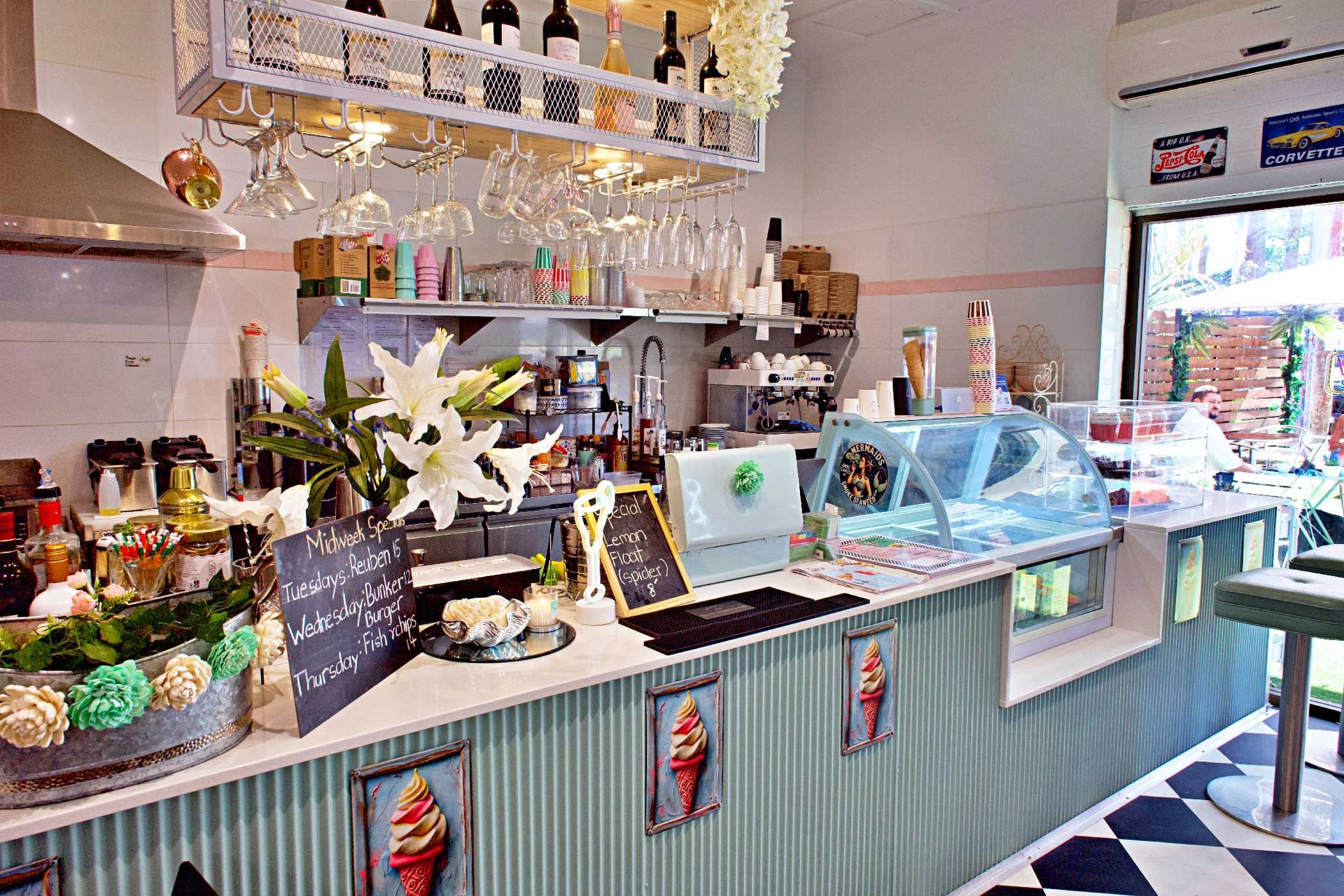 Interior of a cafe with a counter, ice cream display, bar area, and decorative elements.