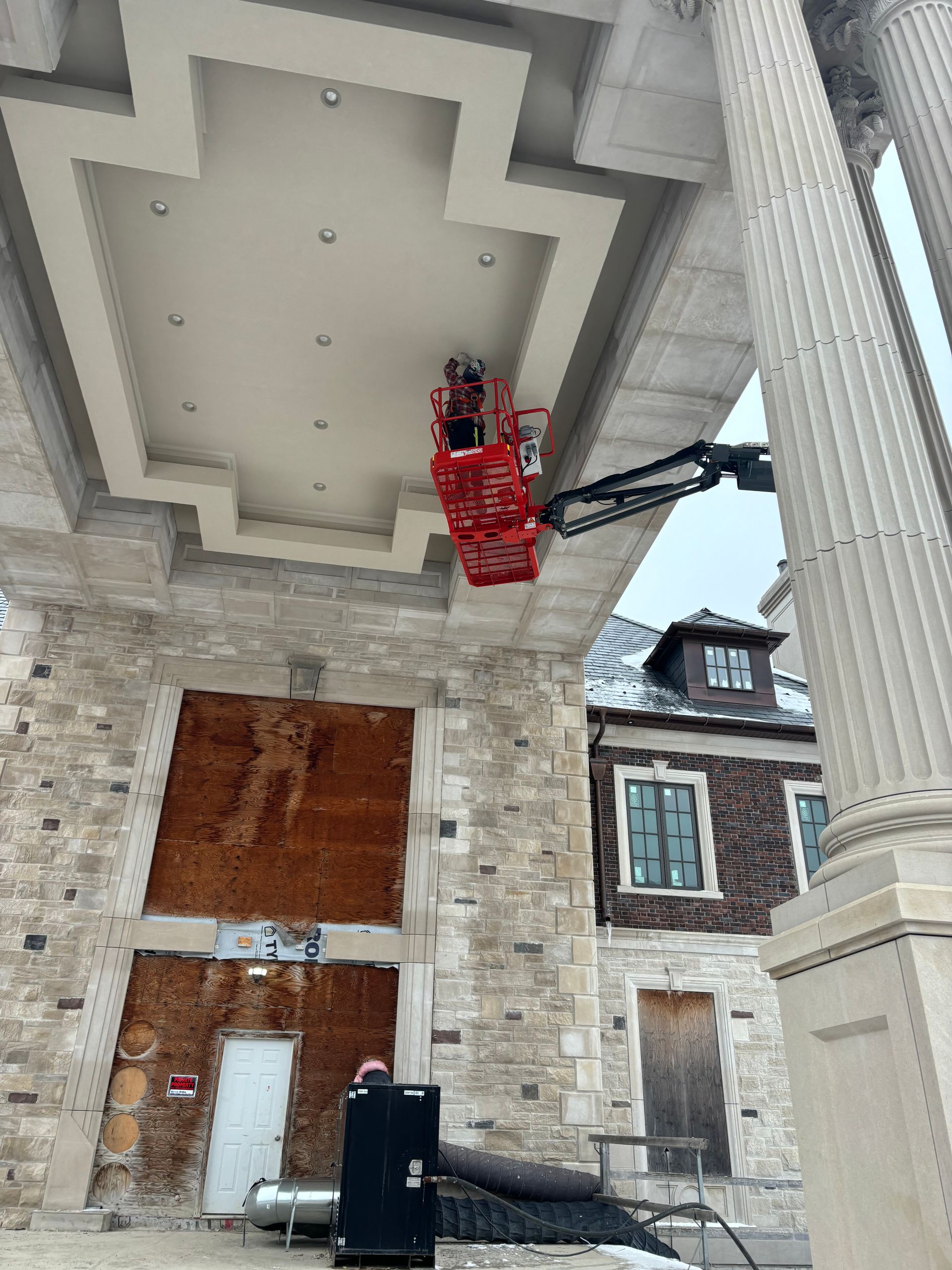 Stone house entrance with columns and a red lift hanging under the porch ceiling