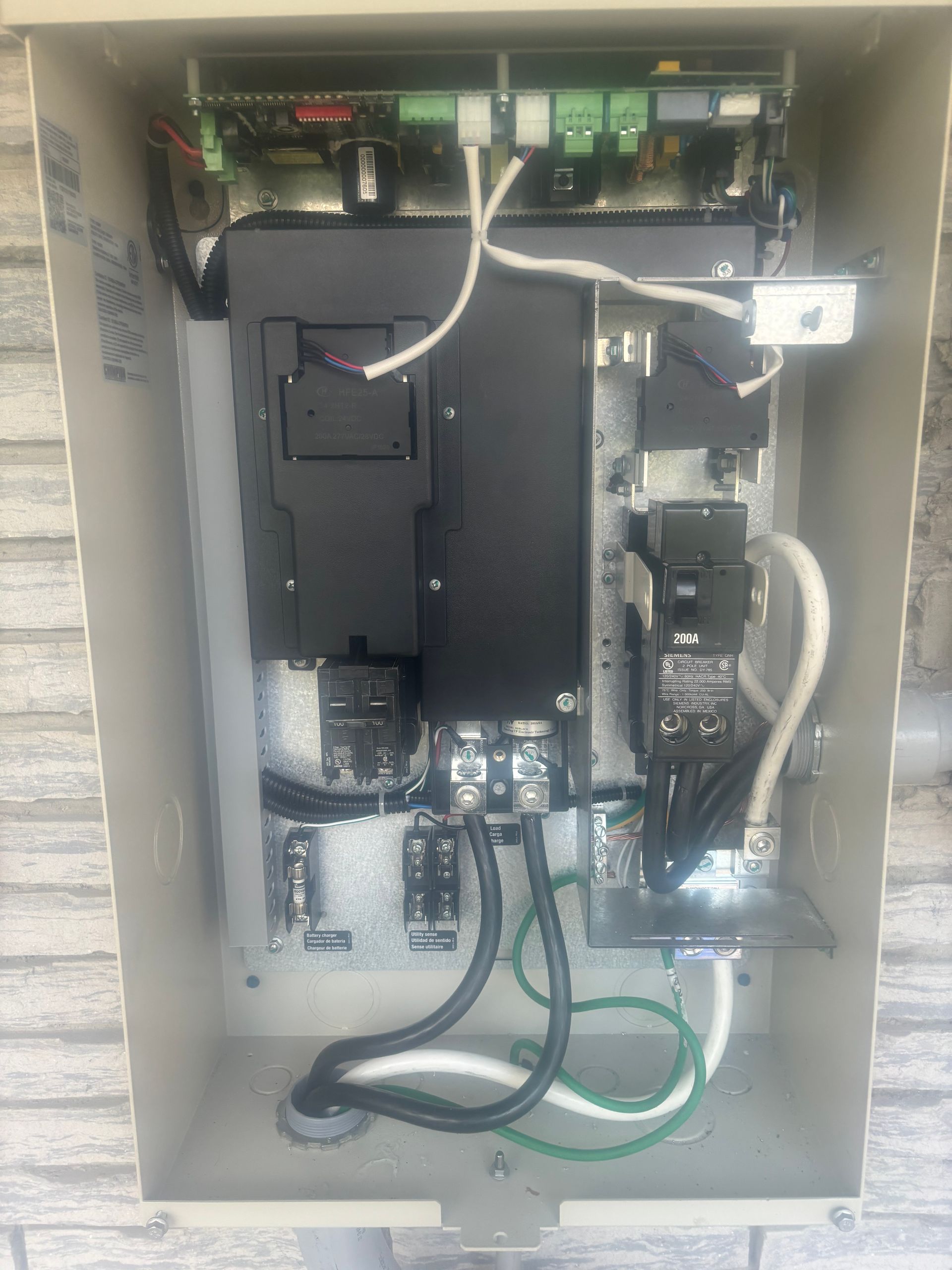 Open electrical control panel with wiring, circuit boards, and cables inside a beige metal cabinet