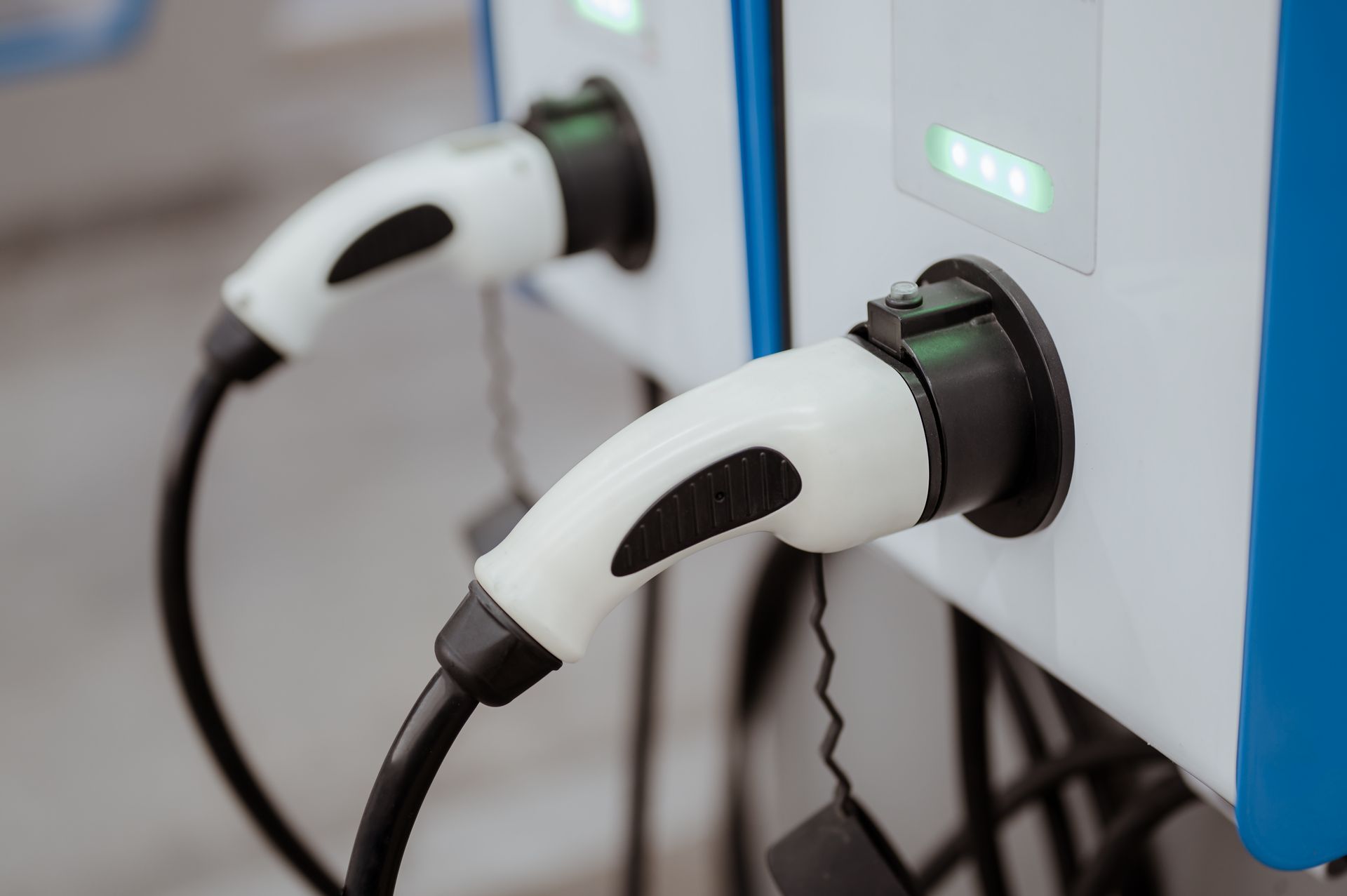 Two white electric vehicle chargers plugged into a charging station