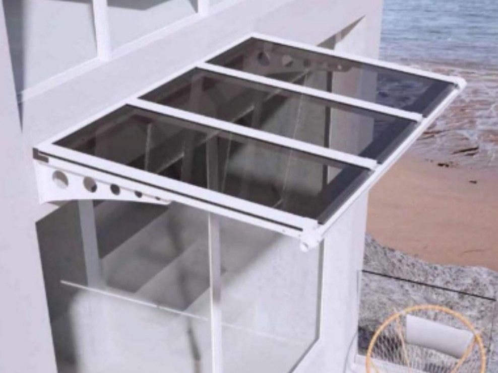Pensilina in vetro con struttura bianca, fissata a un edificio sopra una spiaggia fangosa.
