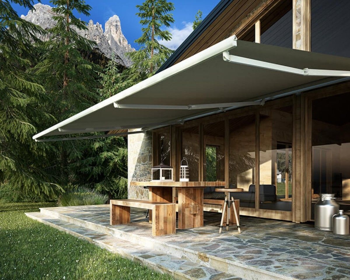 Patio in stile baita moderna con tenda da sole retrattile, mobili in legno e sfondo di una foresta montana.