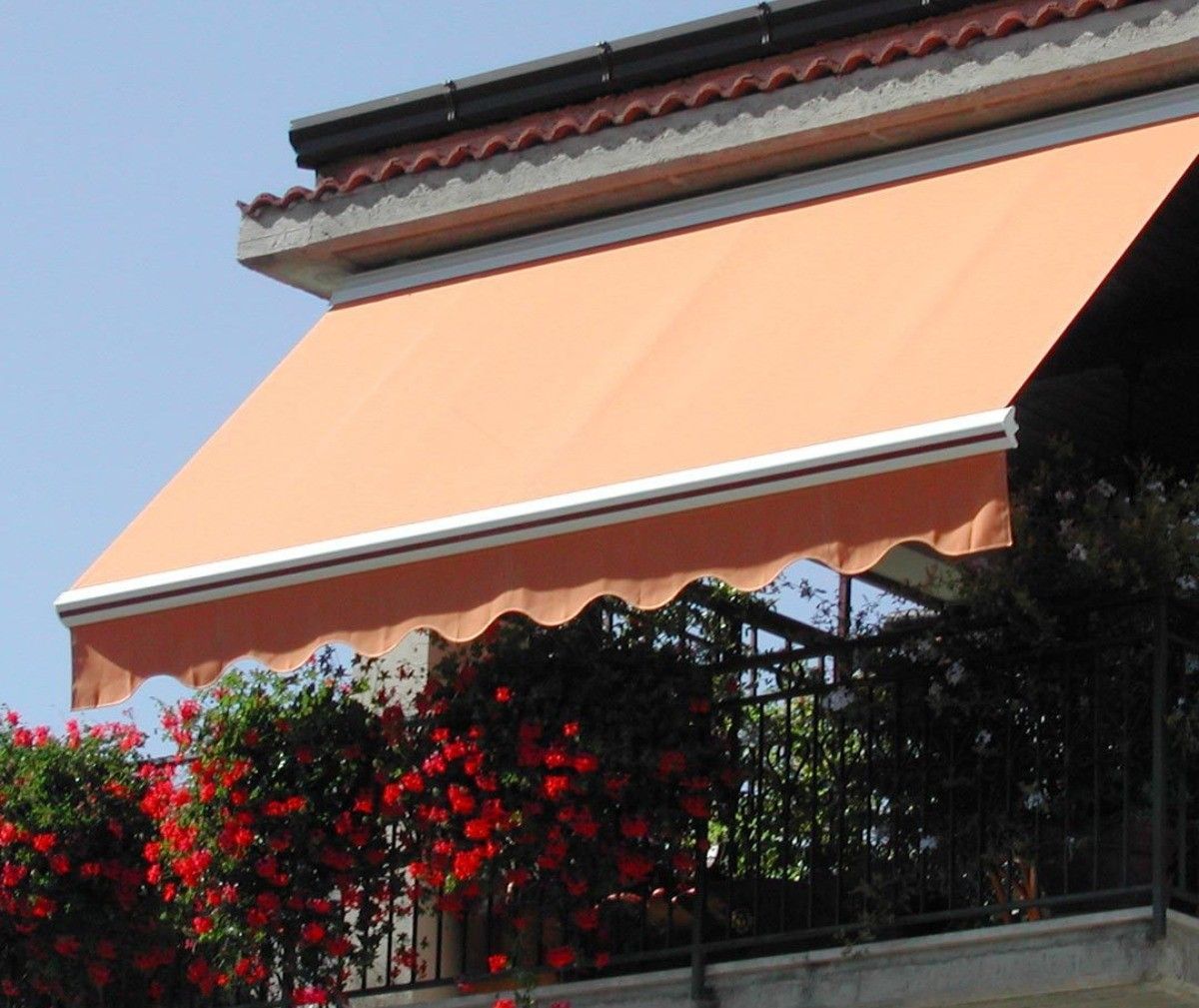Tenda color pesca su un balcone con fiori rossi