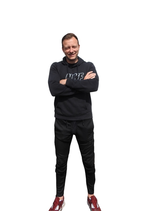 Een man in een zwarte hoodie en zwarte broek staat met zijn armen over elkaar.