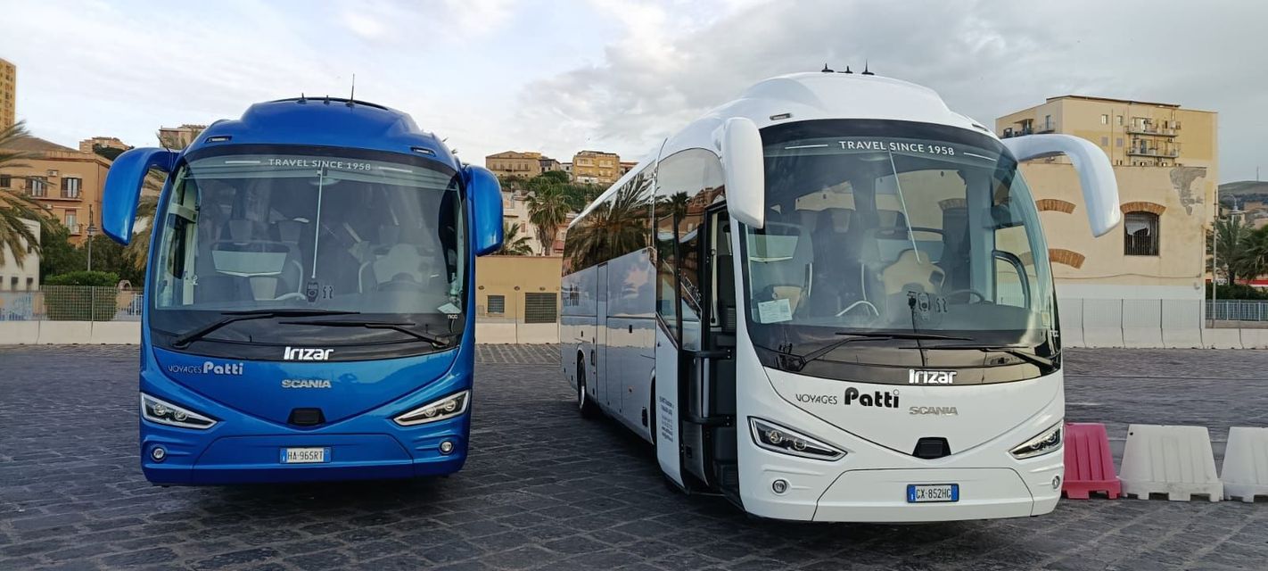 Due autobus, uno blu e uno bianco, parcheggiati uno accanto all'altro in una piazza