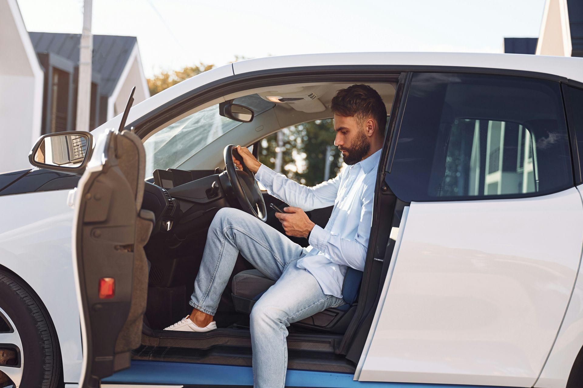 A man is sitting in the driver 's seat of a white car.