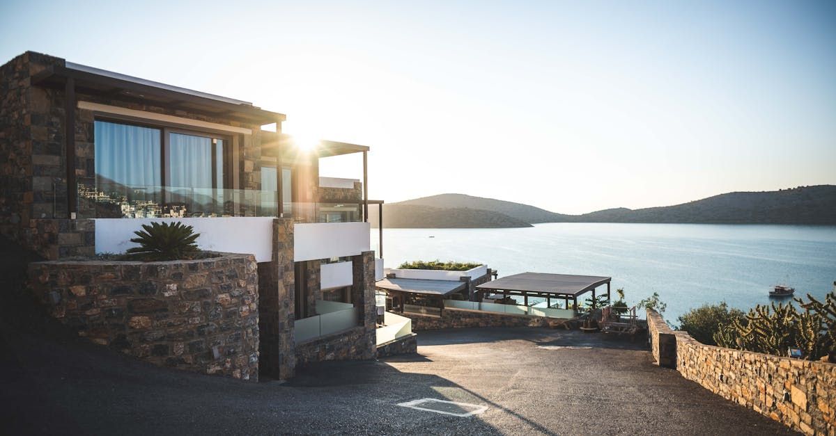A large house is sitting on top of a hill overlooking a body of water.