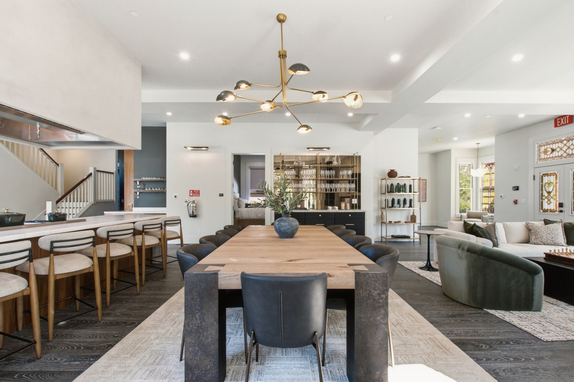 Modern open-concept living and dining room with wood table, bar stools, and sectional sofa