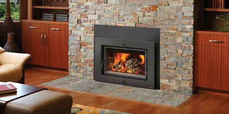A fireplace with burning flames set into a stone wall. Wooden cabinets flank either side of the fireplace.