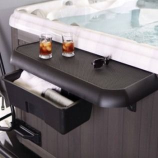 A black hot tub tray with two drinks, sunglasses, and a storage bin with towels.