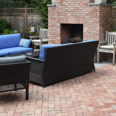 Patio with brick fireplace and wicker furniture with blue cushions.