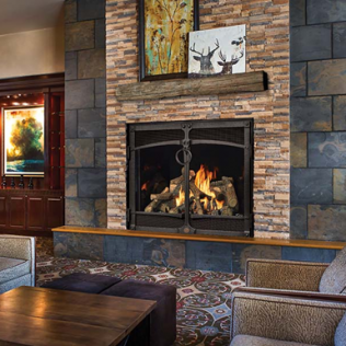 Fireplace with flame, stone facade, and wooden mantel. Two art pieces hang above.