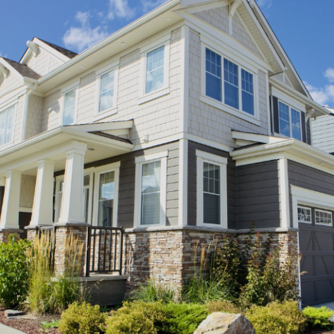 Two-story house with gray and tan siding, stone accents, and a front porch.
