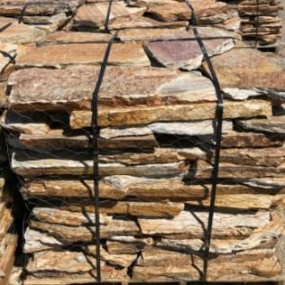 Stack of brown and tan natural stone pavers, bundled for transport.