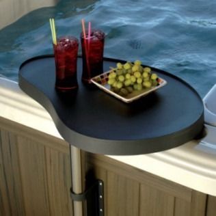 A black tray with drinks and snacks rests on the edge of a hot tub.