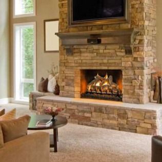 Stone fireplace with TV above, in a beige-colored living room with natural light.