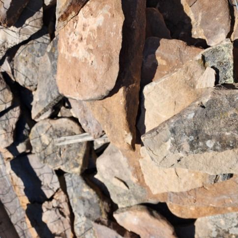 Pile of reddish-brown and gray stones, likely for construction or landscaping.